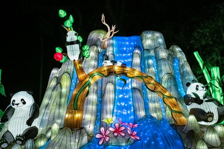 Colorful panda lanterns with waterfall at night festival.
