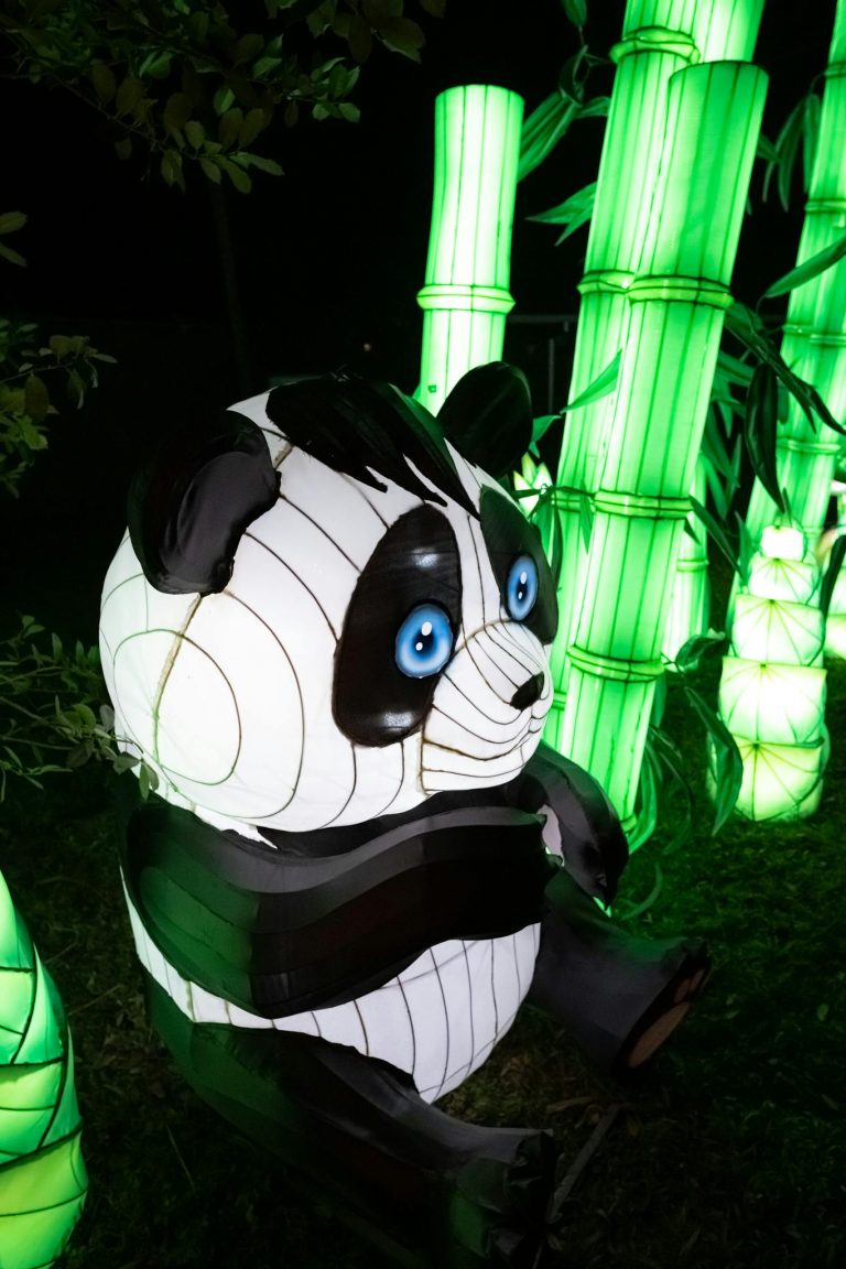 Vibrant panda lantern amidst glowing bamboo displays during night festival.